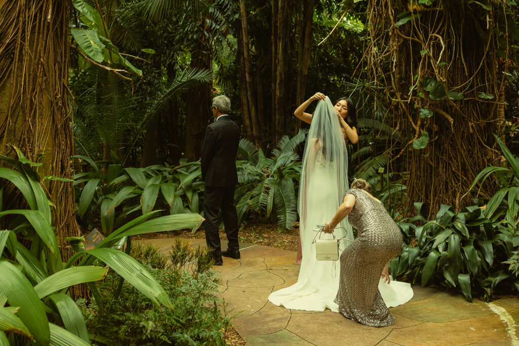 Bride & Father First Look for Wedding in Sunken Gardens in St.Petersburg. Mother of the Bride and Maid of Honor tidying Bride up before First Look with Dad.