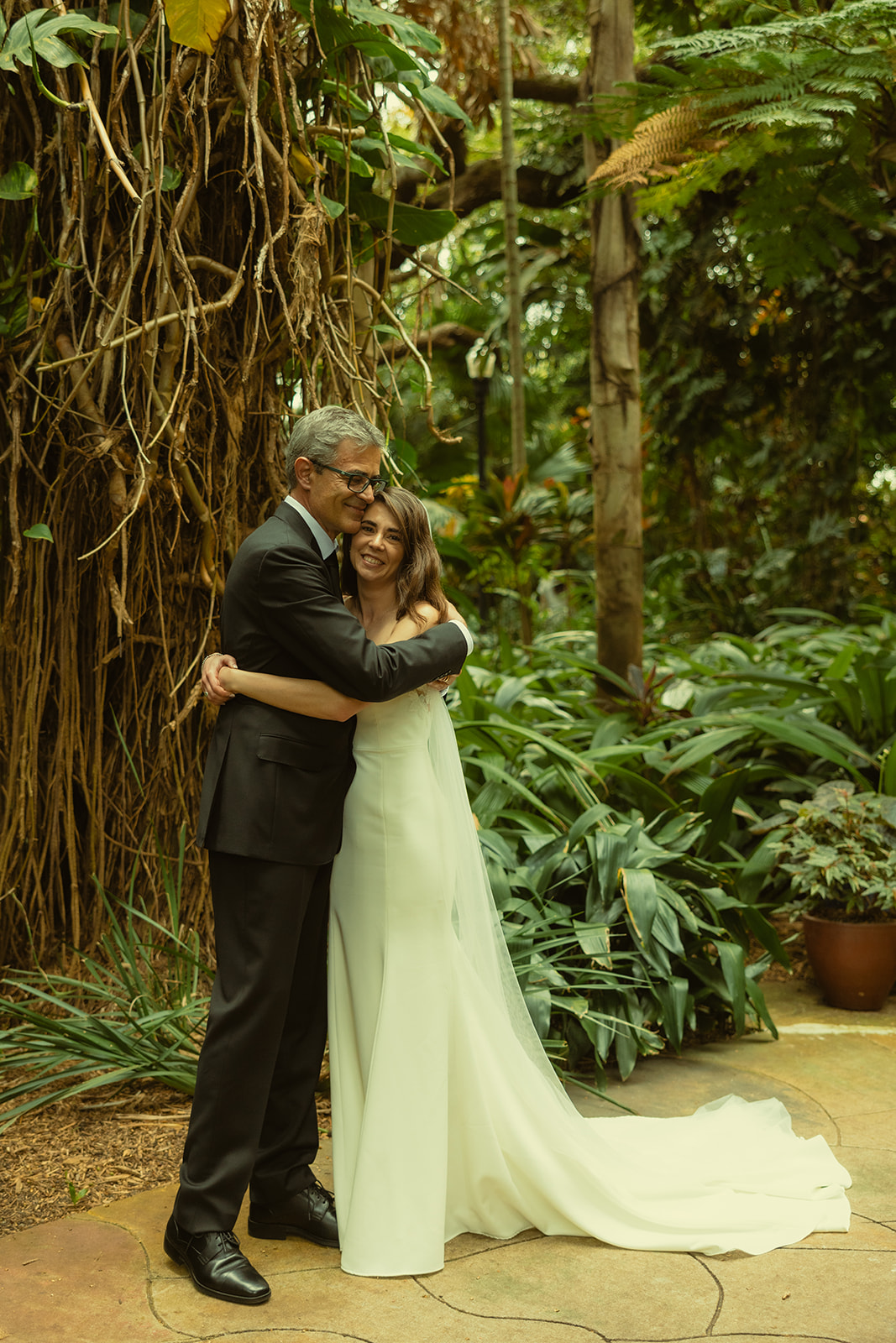 Bride & Father Post First Look for Wedding in Sunken Gardens in St.Petersburg hugging. Bride and Dad hugging