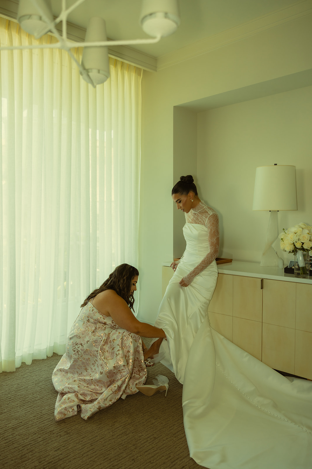 Sister Helping Bride Slip her Wedding Heels on JW Miami Turnberry Resort & Spa in her Essense of Australia Wedding Dress