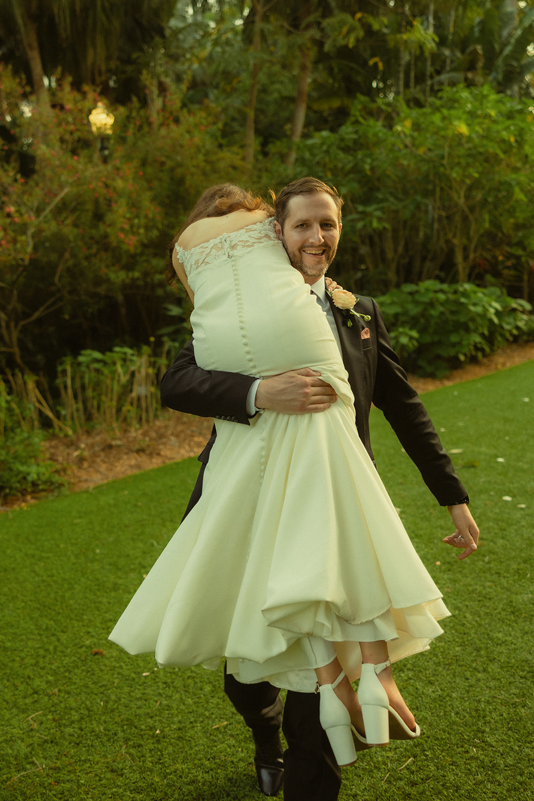 Groom Carrying Bride Over Shoulder Newly Wed Portraits in Garden St.Petersburg Wedding