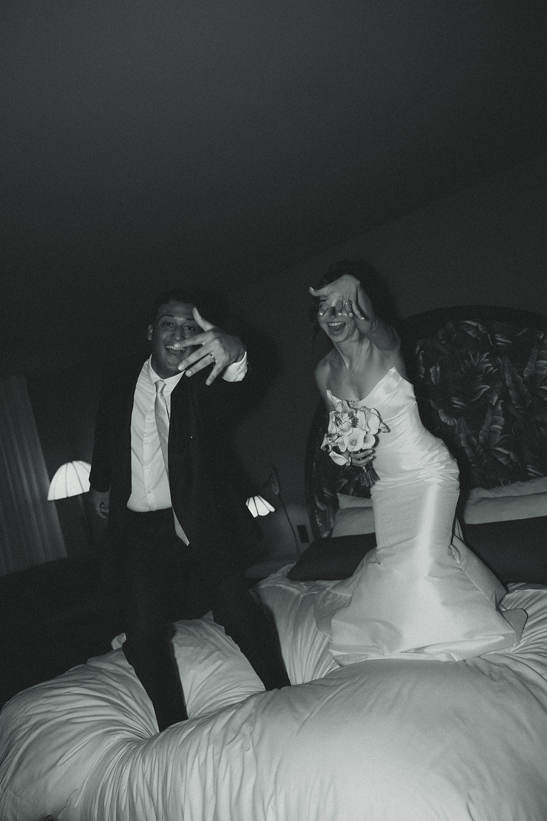 Funky Fun Groom and Bride Jumping in Bed Room Portraits Timeless Wedding in Mayfair Hotel & Garden Black and White