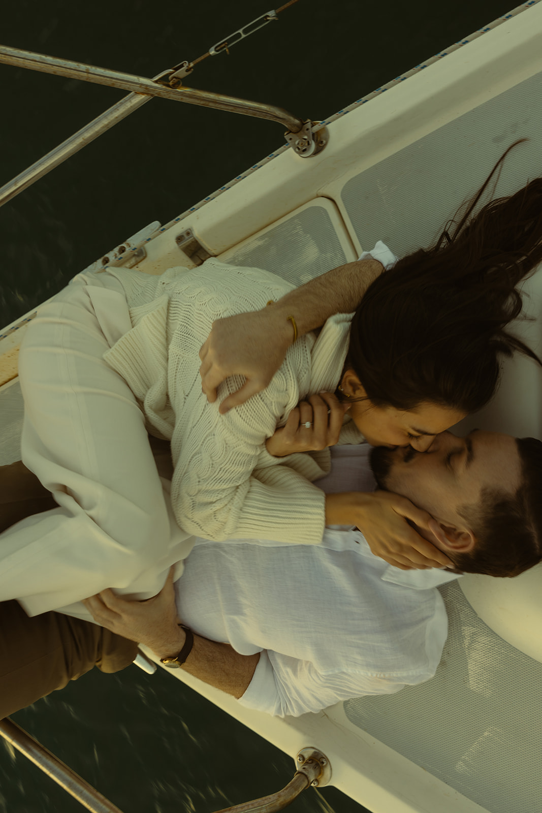 Sailboat Engagement Session in Miami, Laying on Sailboat Cuddled Kissing Couple