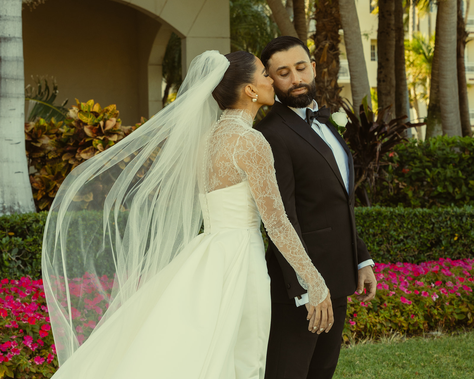 Wide Shot of Bride kissing Groom on Cheek. Editorial Newly Wed Portraits. JW Turnberry Miami. Essense of Australia Wedding Dress and Veil