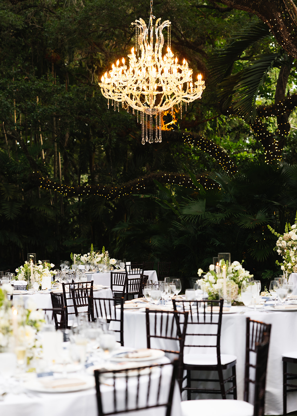 A luxurious New York City wedding day outdoor reception, showcasing an elevated garden dinner design with a statement crystal chandelier.