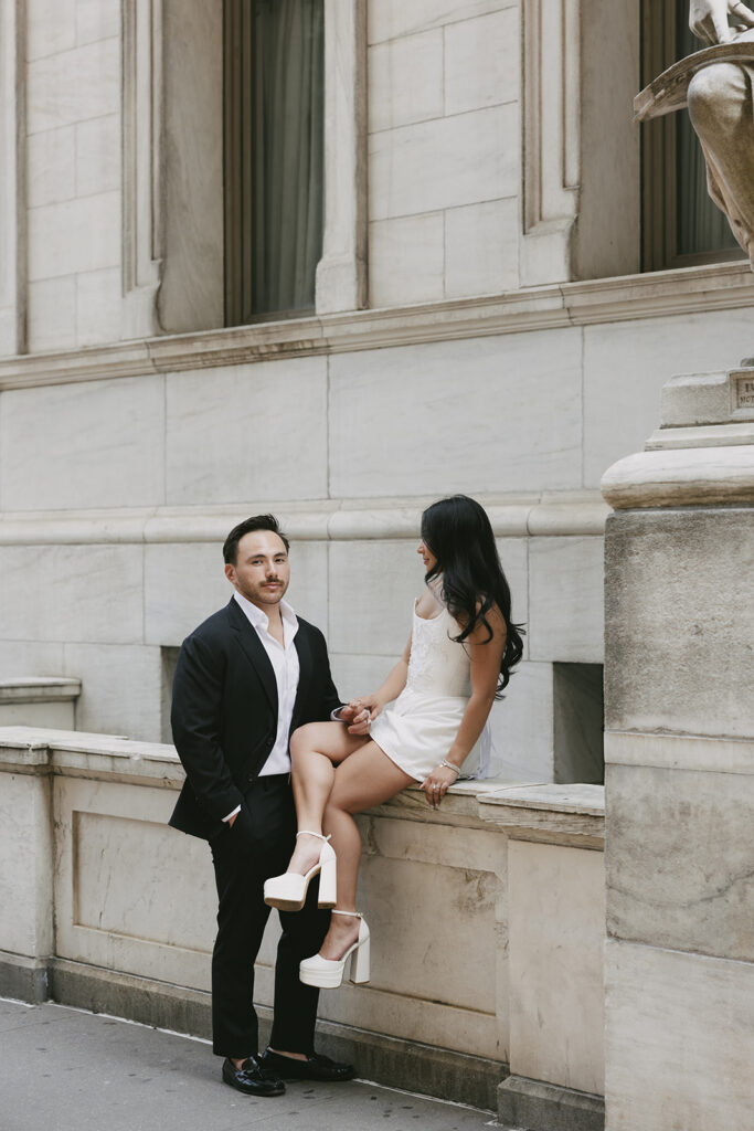 A stylish couple posing during a New York City editorial engagement session outside a classic stone building, illustrating how hiring a wedding planner helps couples seamlessly coordinate pre-wedding events and urban portrait logistics.