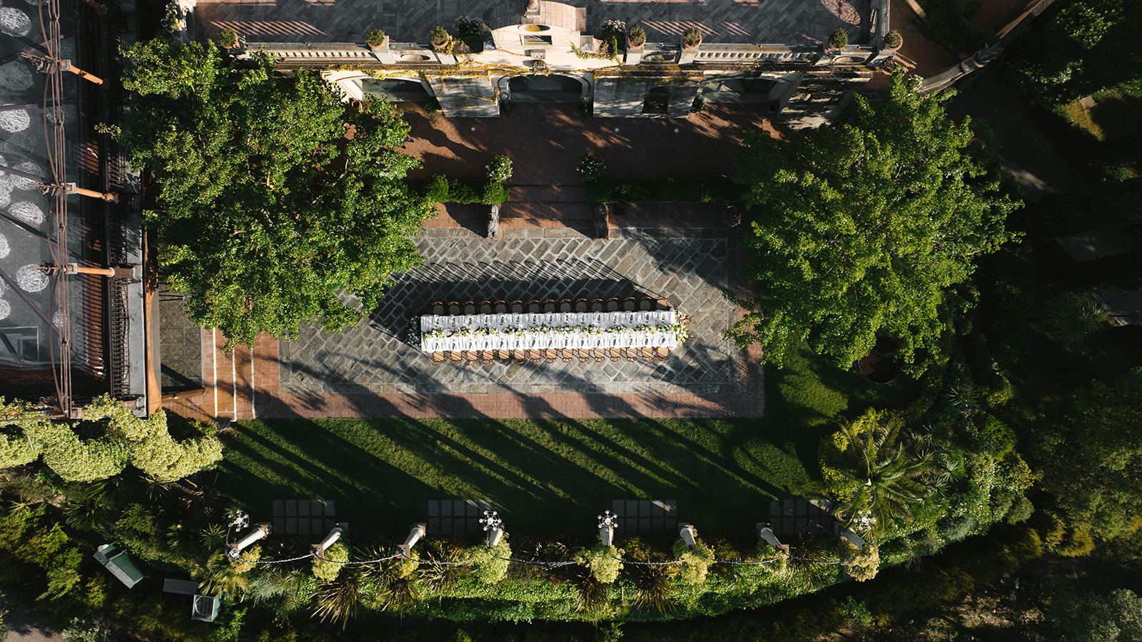 High-angle aerial perspective of a beautifully styled, long banquet table set for a wedding reception in the courtyard of Wedding Tenuta Corbinaia_ Tuscany_ Italy Aileen Ayala Photography-7.jpg, demonstrating the immaculate coordination and execution provided when hiring a wedding planner for a destination event.